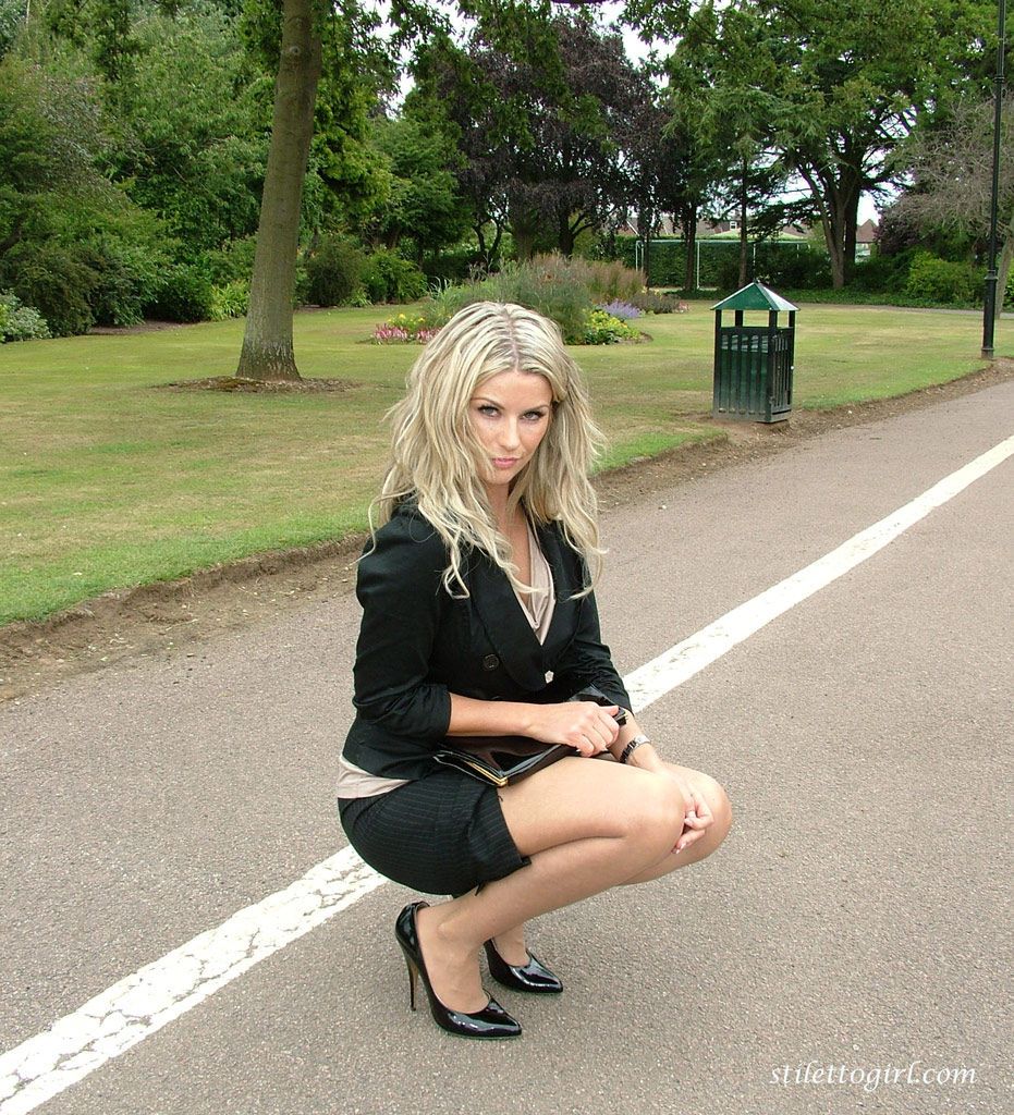 Gekleed Blond secretaris laat uit haar benen en pompen in een openbaar Park