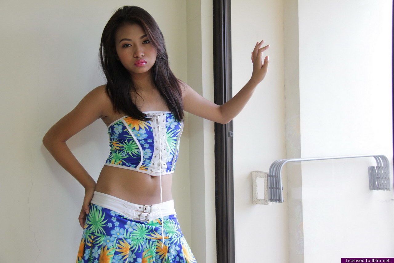 jong Aziatische meisje verwijdert kleding en wit ondergoed in voorzijde van een venster