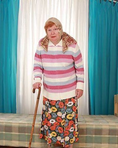 Fett alt Oma Alice Mit Cane posing voll Bekleidet in lange Rock und Socken