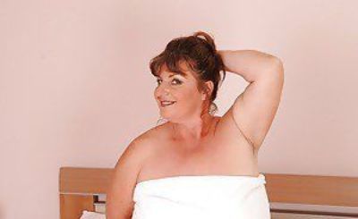 Big busted mature plumper posing barely clothed on the bed