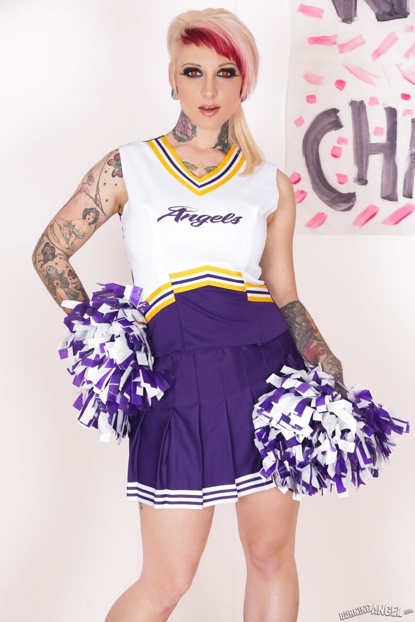 Tattooed chick Scarlet Lavey works free of a cheerleader outfit to pose naked