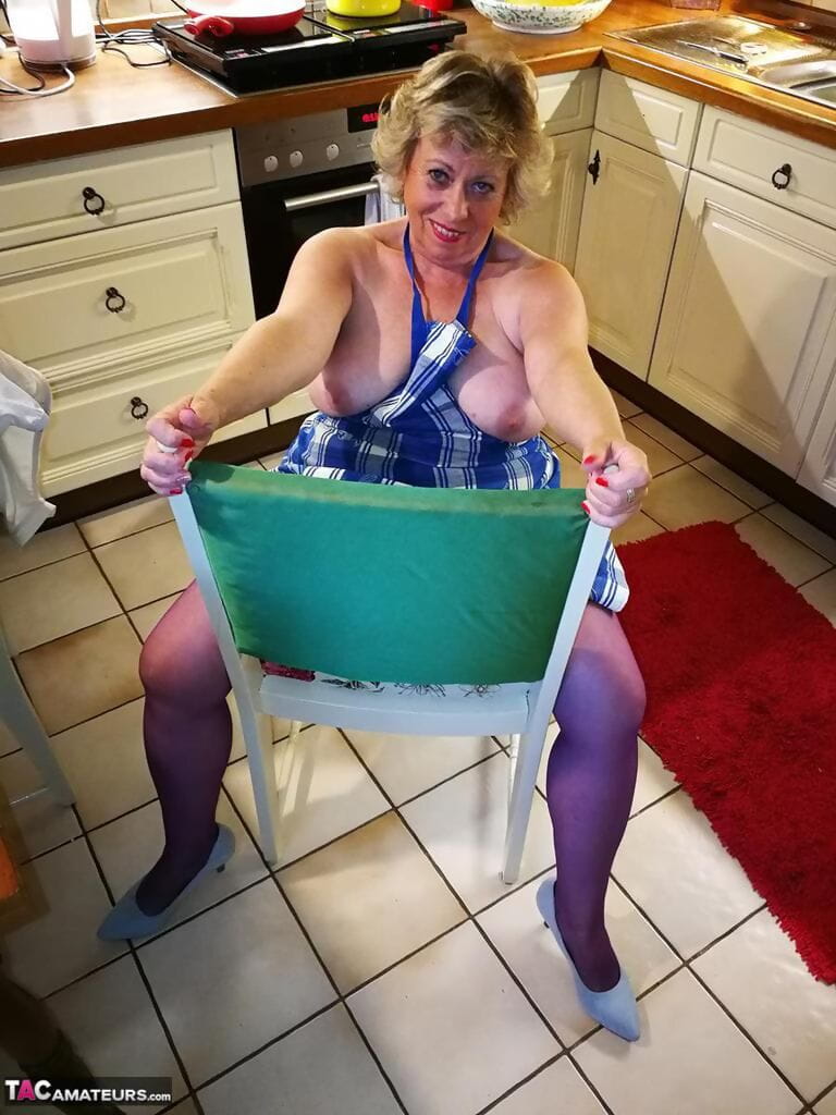 vecchio casalinga Caro prende off Il suo biancheria intima in cucina grembiule e calze
