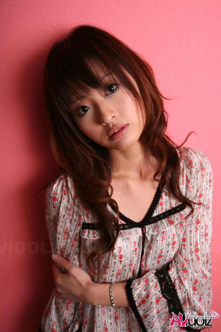 اليابانية نموذج مع A جميلة الوجه تقف الملبس ضد A الوردي الجدار